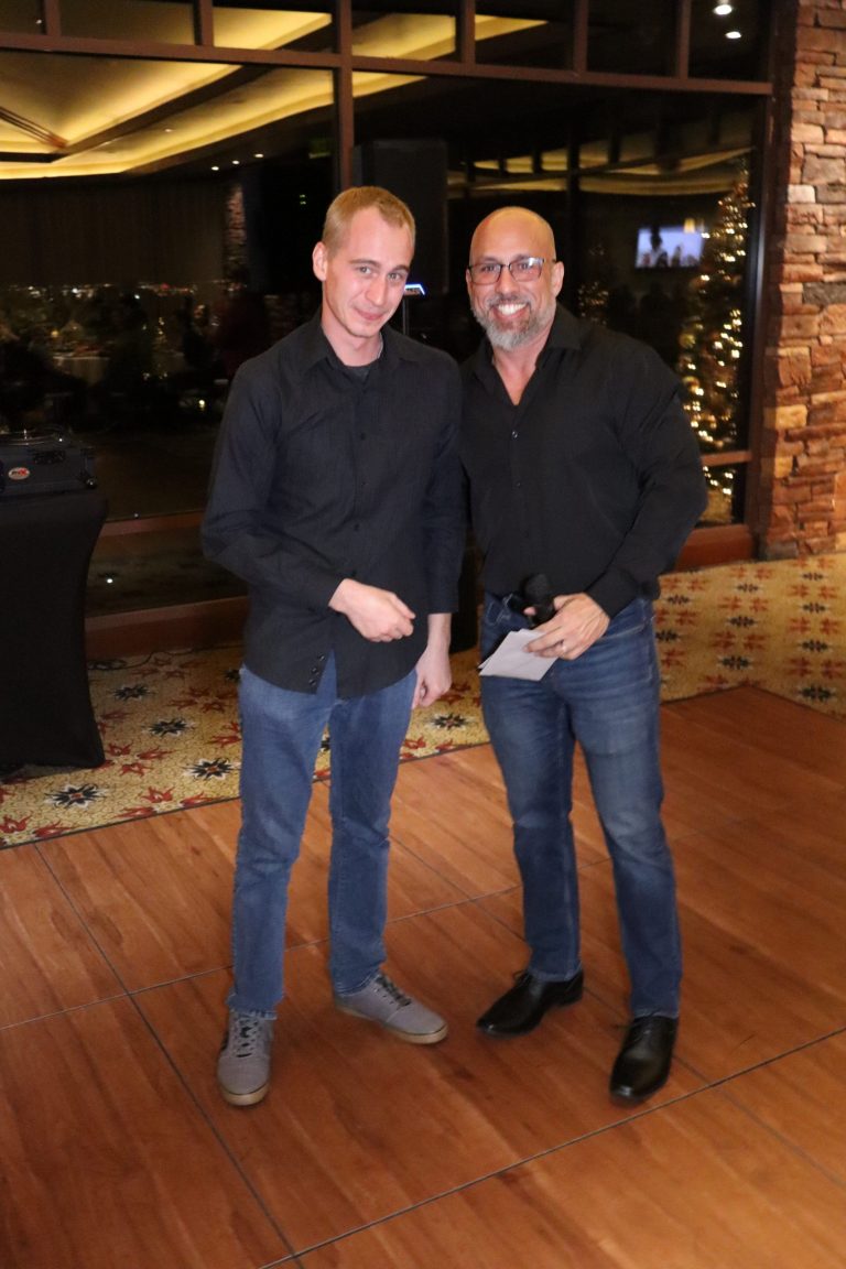 CEO James Farias presenting the Most Resilient Team Member Award at Appreciation Financial's 2024 Holiday Party, with festive decor in the background.